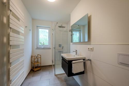 a white bathroom with a sink and a mirror at Dünenquartier Apartment 24 in Zingst