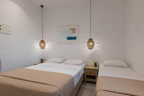 two beds in a white room with two lights at Evagelia's Place in Agios Ioannis Mykonos