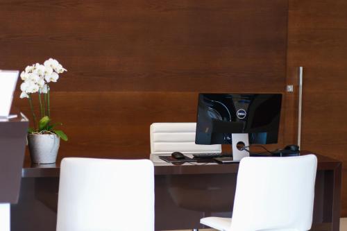 a desk with a computer and two white chairs at Hotel Jardins in Serra
