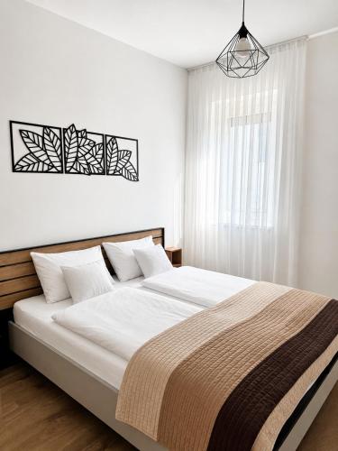a white bedroom with a large bed with white walls at Small Garden Apartman in Sárvár