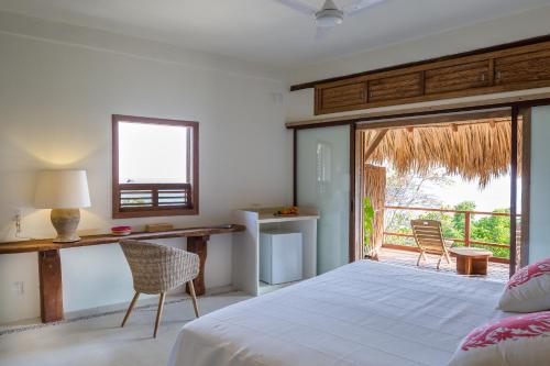 - une chambre avec un lit, un bureau et un balcon dans l'établissement Casa la Ola, à San Agustinillo