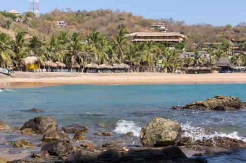 聖奧古斯提尼奧的住宿－Casa la Ola，一片在水中和棕榈树中拥有岩石的海滩