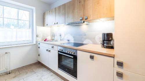 a kitchen with white cabinets and a sink and a window at Haus an der Pferdekoppel Nr 3 in Fehmarn