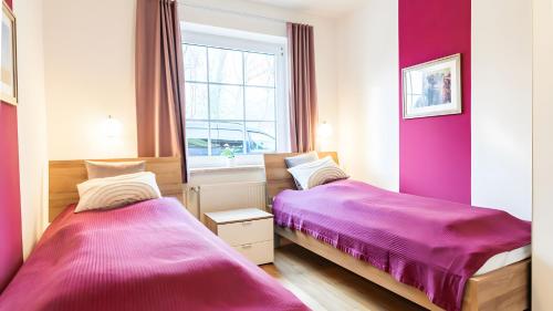 two beds in a room with pink walls at Haus an der Pferdekoppel Nr 3 in Fehmarn