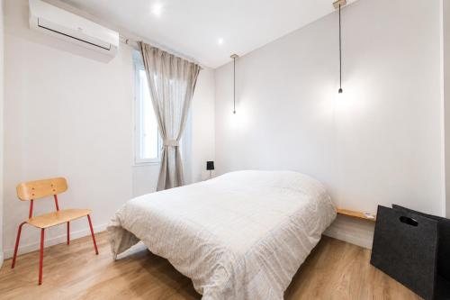 a bedroom with a bed and a chair and a window at F2 balcon à 1minute de la plage in Saint-Raphaël