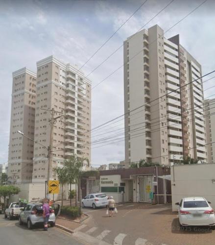 two tall buildings with cars parked in a parking lot at Apto Garcia 01 ao lado do Shopping Pantanal in Cuiabá