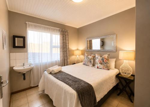 a bedroom with a bed and a sink and a mirror at Zhantique Guest House 2- Unit 12 in Boksburg
