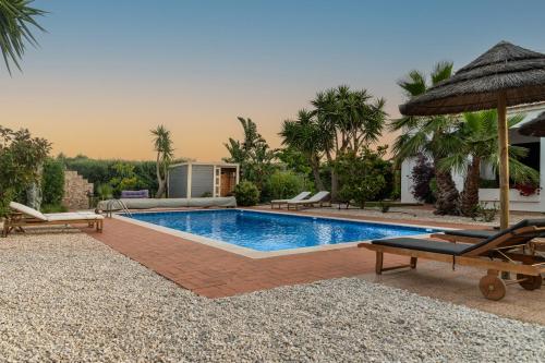 a swimming pool with two chairs and an umbrella at Quinta das Amendoeiras B&B in Nora