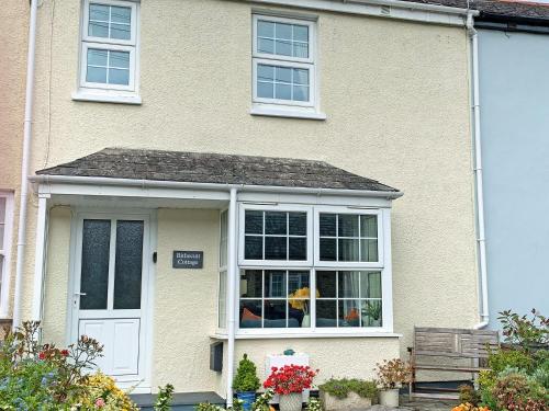 a house with a white door and a window at Bithecutt Cottage in Bude