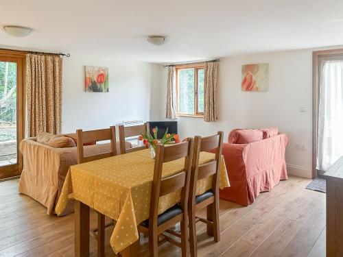 a dining room with a table and a couch at The Old Sawmill One - Uk49336 in Plumpton Green