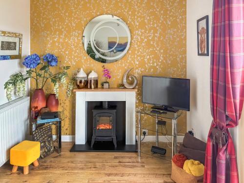 a living room with a fireplace and a tv at Beach Cottage in Gairloch