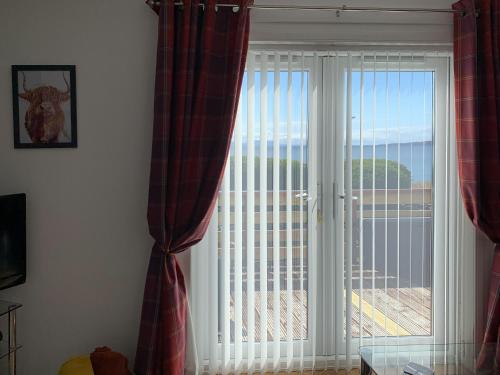 a living room with a large window with blinds at Beach Cottage in Gairloch