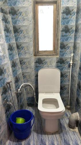 a bathroom with a toilet and a window and a bucket at Yumasham Homestay in Darjeeling