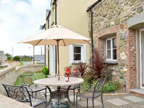 a table and chairs with an umbrella on a patio at Cart-Tws Bach - Om8 in Treffynnon 