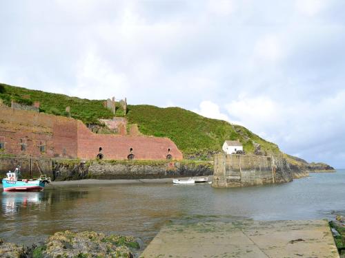 a boat in the water next to a castle at Cart-Tws Bach - Om8 in Treffynnon 