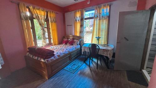 a bedroom with a bed and a table and windows at Yumasham Homestay in Darjeeling