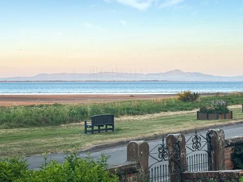 a bench sitting on the grass near the beach at The Haven in Annan