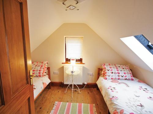 a attic bedroom with two beds and a window at Plum Cottage in Anderby