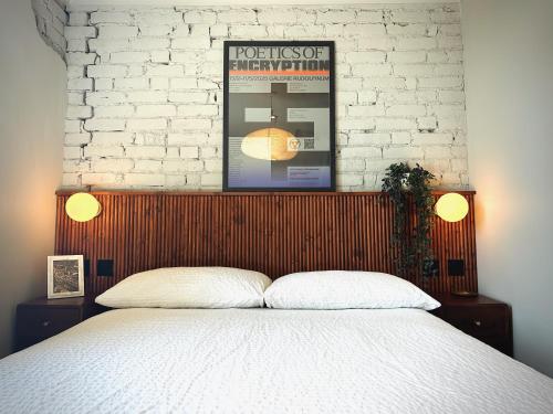 a bedroom with a bed and a white brick wall at Margate Manor - Rooms by the Sea in Margate
