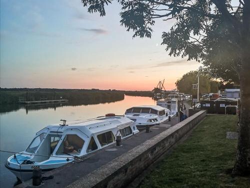 two boats are docked at a dock on a river at Elm Barn Lodge in Freethorpe