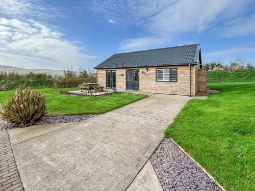 a small house with a garden and a patio at Magnolia Lodge - Uk51603 in Peel