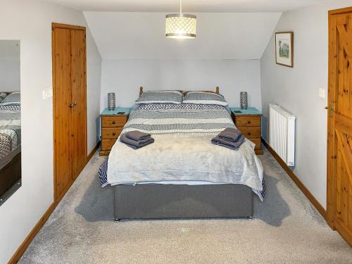 a bedroom with a large bed and two wooden cabinets at Cider Cottage - Uk11861 in North Tamerton