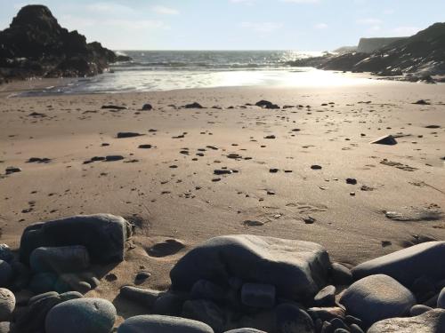 a beach with rocks on the sand and the ocean at Watersreach in Collieston