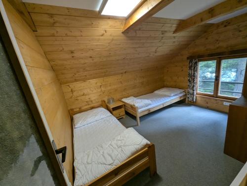 an attic room with two beds and a window at Chata Oliva in Planá nad Lužnicí