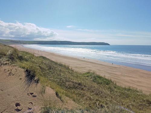 a beach with people walking on the sand and the ocean at Lodge 33 in Woolacombe