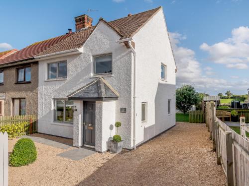 a white house with a wooden fence at White Stag Cottage in Bamburgh