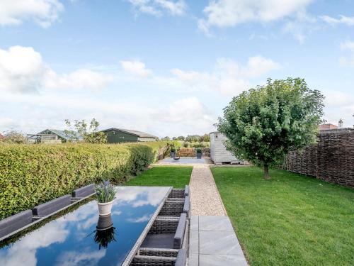 a garden with a reflecting pool and a tree at White Stag Cottage in Bamburgh