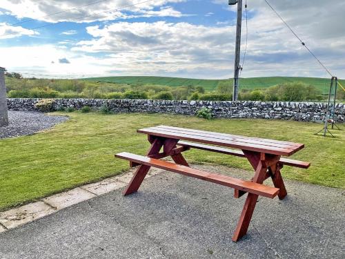 a wooden bench sitting next to a stone wall at Broughton in Newton Stewart