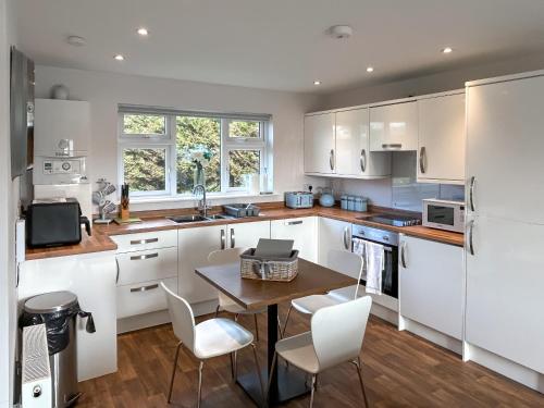 a kitchen with white cabinets and a table and chairs at Fern Lodge - Uk51604 in Peel