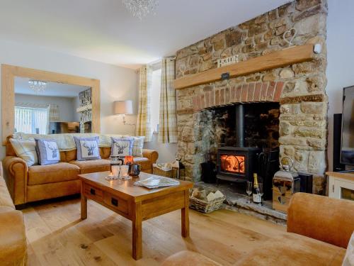 a living room with a large stone fireplace at Honeycott in Crickhowell
