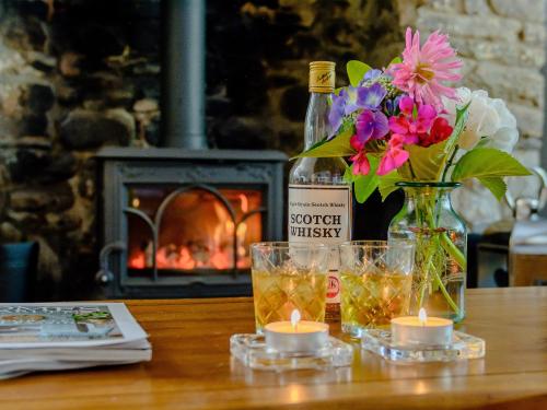 a table with flowers and candles and a bottle of whiskey at Honeycott in Crickhowell