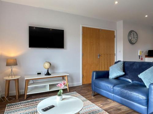 a living room with a blue couch and a tv at Wisteria Lodge - Uk51605 in Peel