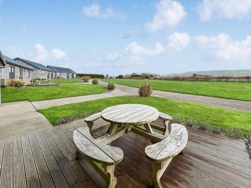 a picnic table and two benches on a wooden deck at Primrose Lodge - Uk51602 in Peel