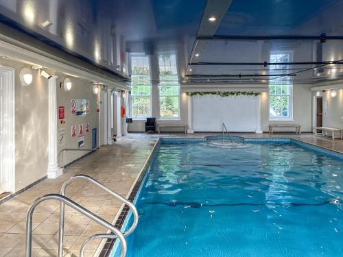 a large pool with blue water in a building at Spruce Cottage in Tywardreath