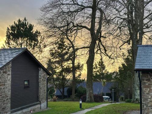 a house with a tree next to a building at Spruce Cottage in Tywardreath