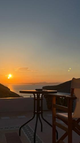a table and a chair on a balcony with the sunset at Sun Holiday Kea Private Pool Sea View in Pisses