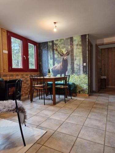 a dining room with a painting of a deer on the wall at Chalet De La Forêt - 6 personnes in Saint-Sauveur