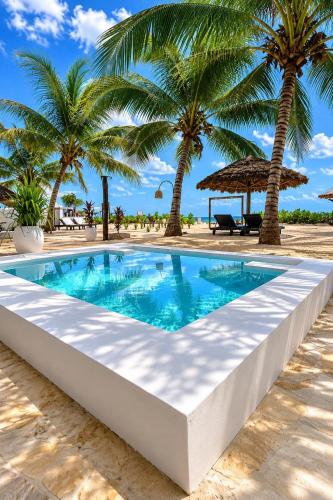 ein Swimmingpool am Strand mit Palmen in der Unterkunft SOFIA SEA VIEW - Beach Boutique Hotel by Sofia Collection in Pwani Mchangani