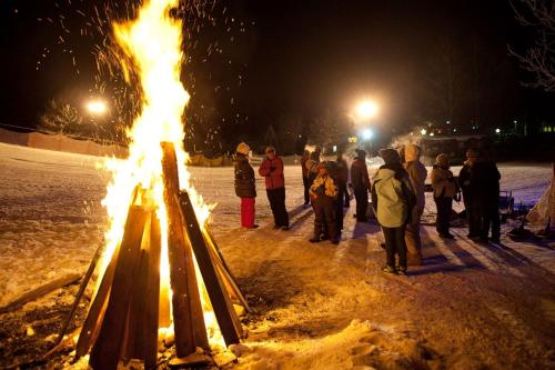 a group of people standing around a fire in the snow at Kinderhotel Appelhof in Mürzsteg