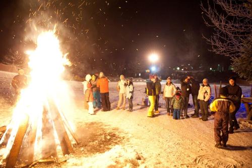a group of people standing around a fire in the snow at Kinderhotel Appelhof in Mürzsteg