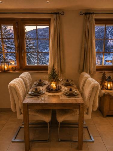 a dining room with a table and chairs and windows at Chalet Nunavut, Ski in - Ski out with Complimentary Spa Access in Zermatt