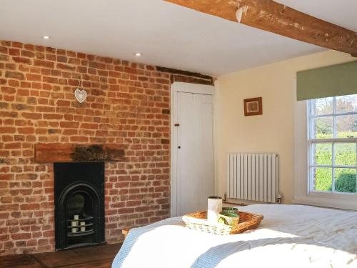 a bedroom with a brick wall with a bed and a fireplace at Amphlett Cottage in Bredon