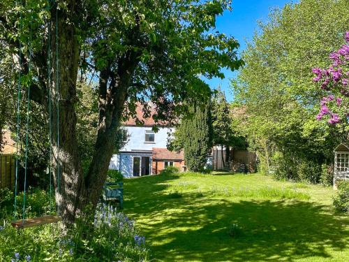 a yard with a white house and a tree at Amphlett Cottage in Bredon