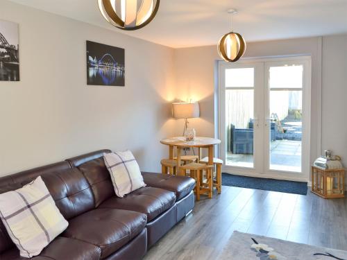 a living room with a leather couch and a table at Seashells By The Sea in Newbiggin-by-the-Sea