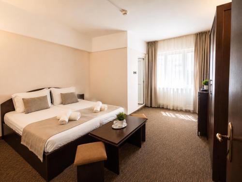 a hotel room with a large bed and a table at Casa Mario in Eforie Nord