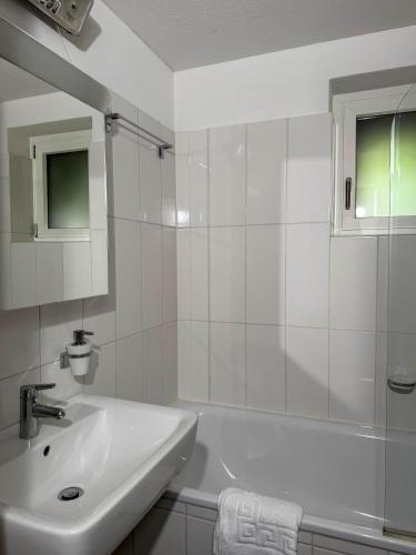 a white bathroom with a sink and a bath tub at Rustico Al Stradon by HolAp SA in Avegno